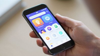 Mão segurando um smartphone com aplicativos na tela.